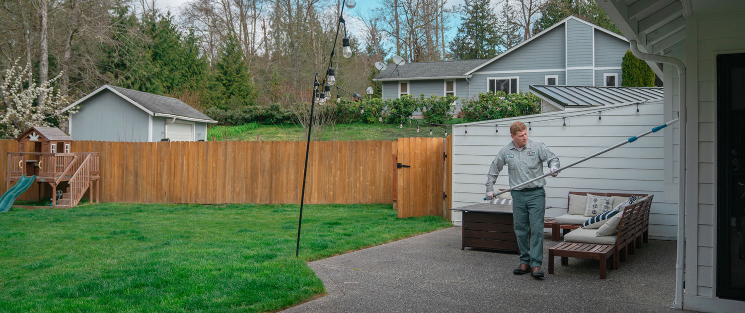 Technician performing exterior spider sweep treatment